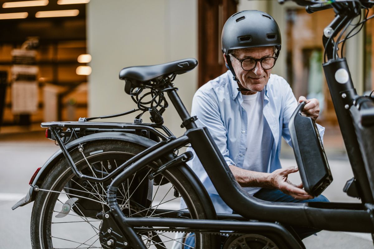 Senior man changing battery on electric bicycle