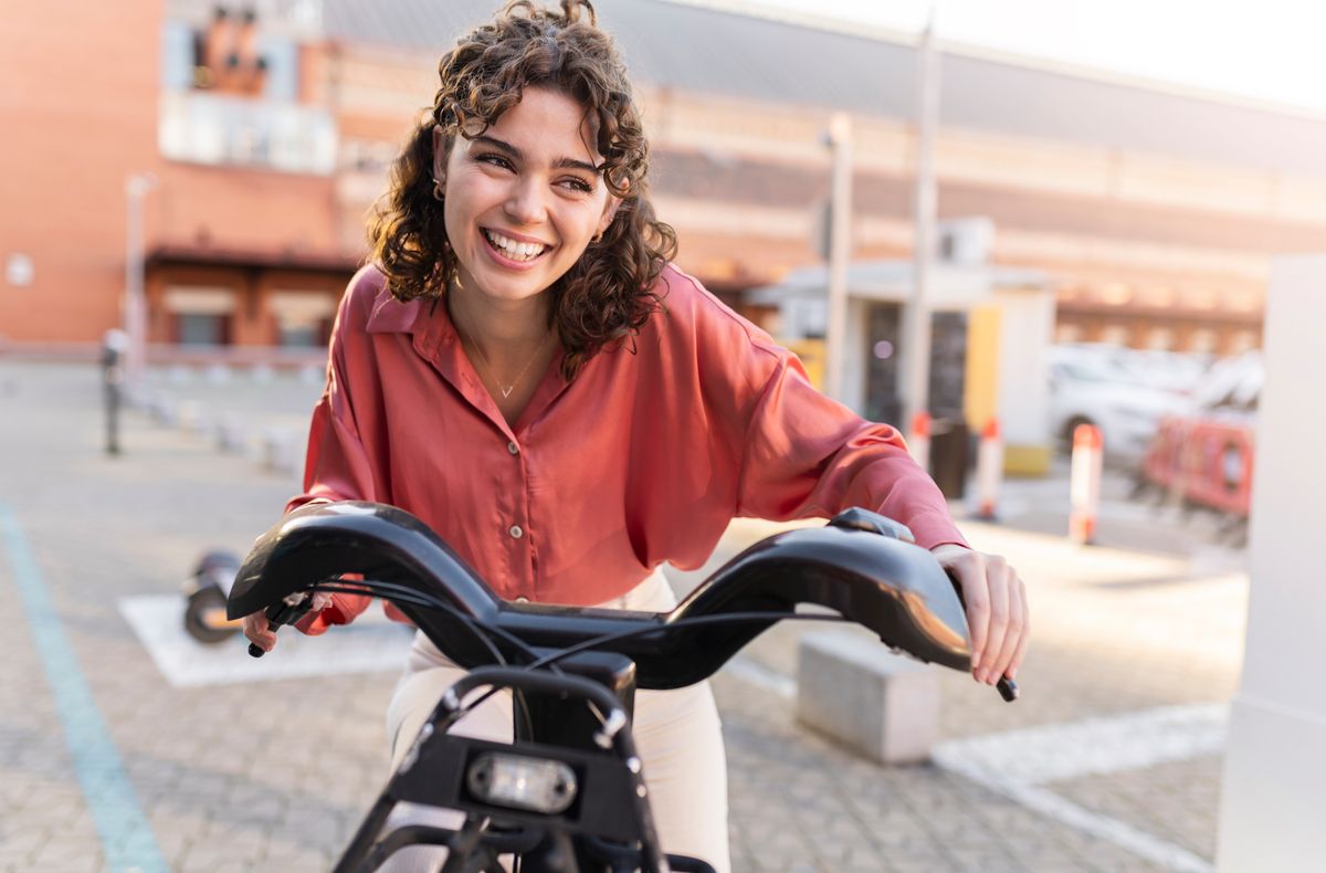 Happy woman riding electric bicycle at station